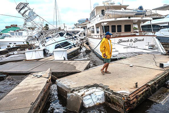 A man inspects damage to a marina as boats are partially submerged in the aftermath of Hurricane Ian in Fort Myers, Florida, on September 29, 2022. - Hurricane Ian left much of coastal southwest Florida in darkness early on Thursday, bringing 