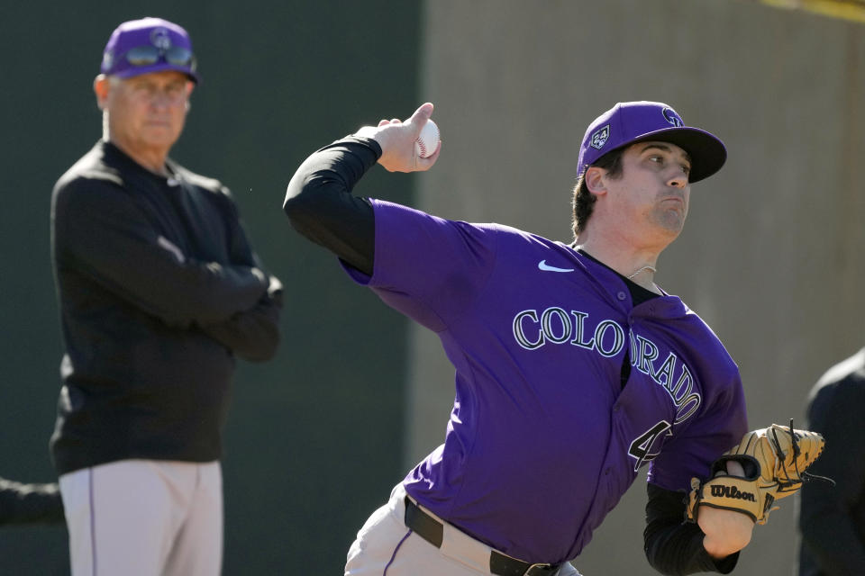 Colorado Rockies starting pitcher Cal Quantrill, right, throws as Rockies manager Bud Black, left, looks on during spring training baseball workouts Friday, Feb. 16, 2024, in Scottsdale, Ariz. (AP Photo/Ross D. Franklin)