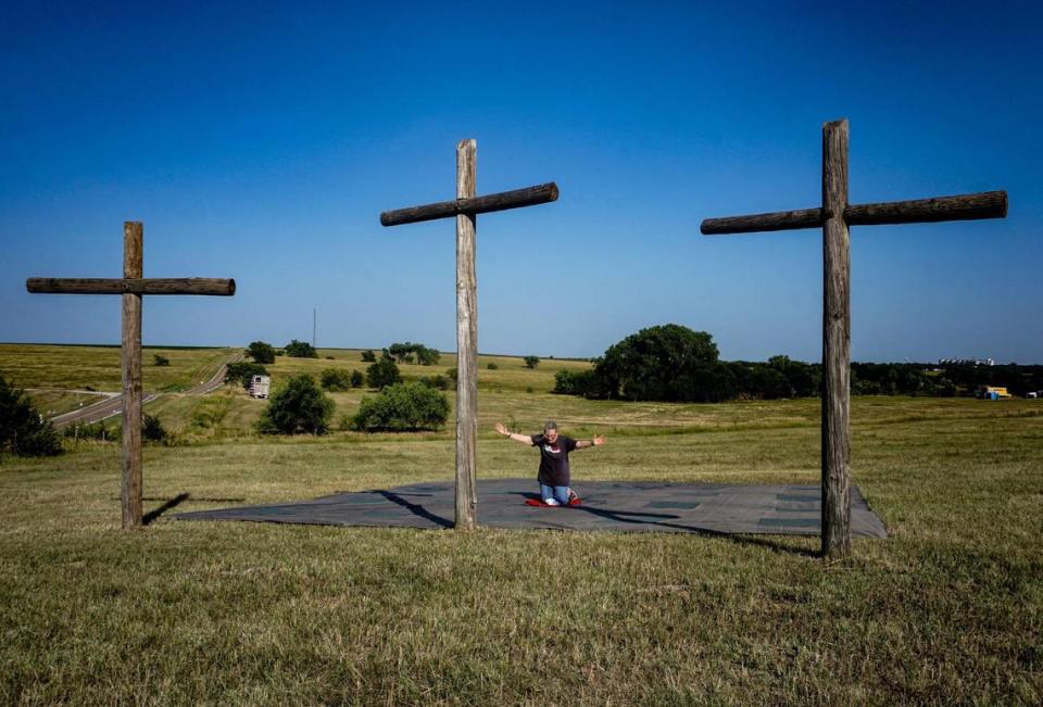 Carmen Metzger from Topeka prays on her knees before crosses, Friday, July 22, 2021 near the geographic center of the 48 contiguous U.S. states in Lebanon, Kansas. In the distance a voice calls out Òlift up your handsÓ over a speaker and Metzger remembers the verse 2 Chronicles 7 from the Bible as she prays.