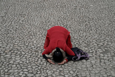 A Buddhist prays in front of the site of Beichuan Middle School which was buried by boulders in the 2008 Sichuan earthquake, ahead of Qingming Festival or Tomb Sweeping Day in the city of Beichuan, Sichuan province, China, April 4, 2018. REUTERS/Jason Lee