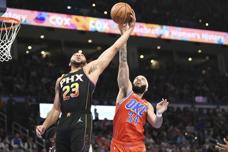 Oklahoma City Thunder forward Kenrich Williams (34) and Phoenix Suns guard Eric Gordon (23) reach for a rebound during the second half of an NBA basketball game Friday, March 29, 2024, in Oklahoma City. (AP Photo/Kyle Phillips)