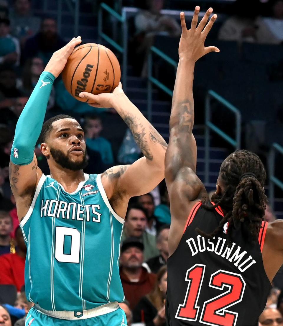Charlotte Hornets forward Miles Bridges, left, lines up a three-point shot over Chicago Bulls guard Ayo Dosunmu, right, during second half action on Monday, January 8, 2024 at Spectrum Center in Charlotte, NC. The Bulls defeated the Hornets in overtime 119-112.
