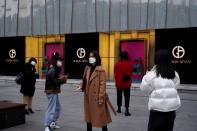 People wearing face masks are seen outside a Giorgio Armani store at a shopping mall in Wuhan