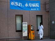 A hospital staff member walks past under a banner reading "Gambare or cheer-up Eiju Hospital" presented by a local residents' group members at Eiju General Hospital in Tokyo