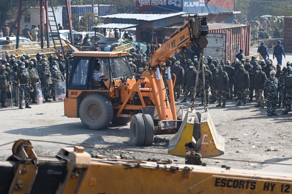 Security forces (back) watch as police sets up road blocks at the Delhi-Haryana state border in Singhu on January 27, 2021, as police closed several main roads a day after farmers went on the rampage in the capital, leaving one person dead and dozens injured. (Photo by Money SHARMA / AFP) / The erroneous mention[s] appearing in the metadata of this photo by Money SHARMA has been modified in AFP systems in the following manner: [at the Delhi-Haryana state border in Singhu] instead of [at Singhu border in New Delhi]. Please immediately remove the erroneous mention[s] from all your online services and delete it (them) from your servers. If you have been authorized by AFP to distribute it (them) to third parties, please ensure that the same actions are carried out by them. Failure to promptly comply with these instructions will entail liability on your part for any continued or post notification usage. Therefore we thank you very much for all your attention and prompt action. We are sorry for the inconvenience this notification may cause and remain at your disposal for any further information you may require. (Photo by MONEY SHARMA/AFP via Getty Images)