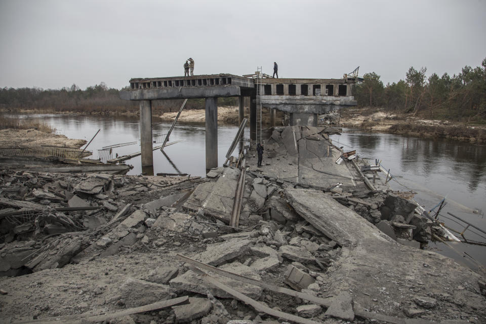 Ukrainian servicemen stand on a destroyed bridge between the village of Dytiatky and Chernobyl, Ukraine, Tuesday, April 5, 2022. (AP Photo/Oleksandr Ratushniak)