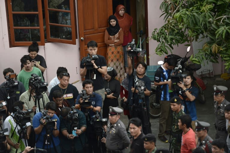 Residents (top) watch policemen search apartment blocks on the outskirts of Bangkok on August 30, 2015