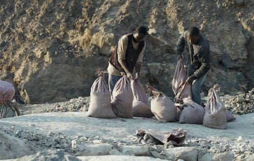 <span class="caption">Labourers load sacks of cobalt onto bicycles at Mutoshi mine in July 2021. </span> <span class="attribution"><span class="source">Roy Maconachie</span></span>