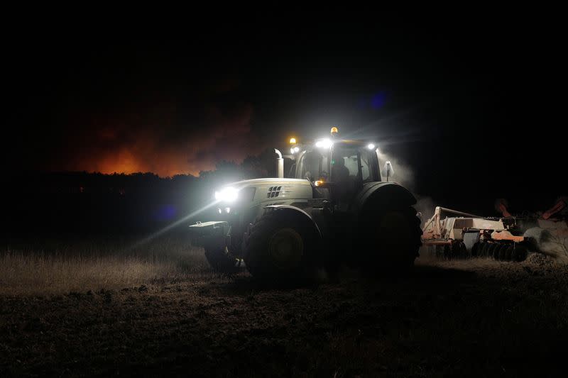 A tractor cleans up land during a wildfire in Aljesur