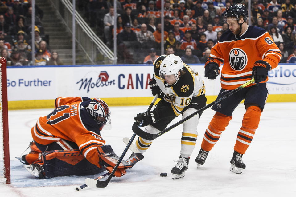 Boston Bruins left wing Anders Bjork (10) is stopped by Edmonton Oilers goalie Mike Smith (41) as Adam Larsson (6) defends during the first period of an NHL hockey game, Wednesday, Feb. 19, 2020 in Edmonton, Alberta. (Jason Franson/The Canadian Press via AP)