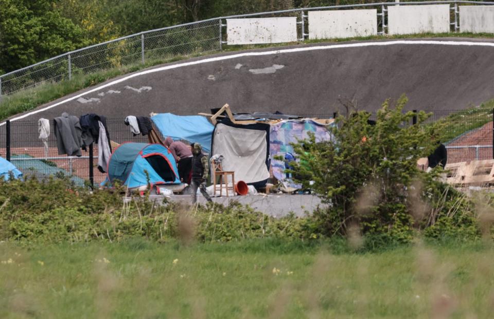 Migrants wander around a makeshift camp near Calais on 23 April. (AFP via Getty Images)