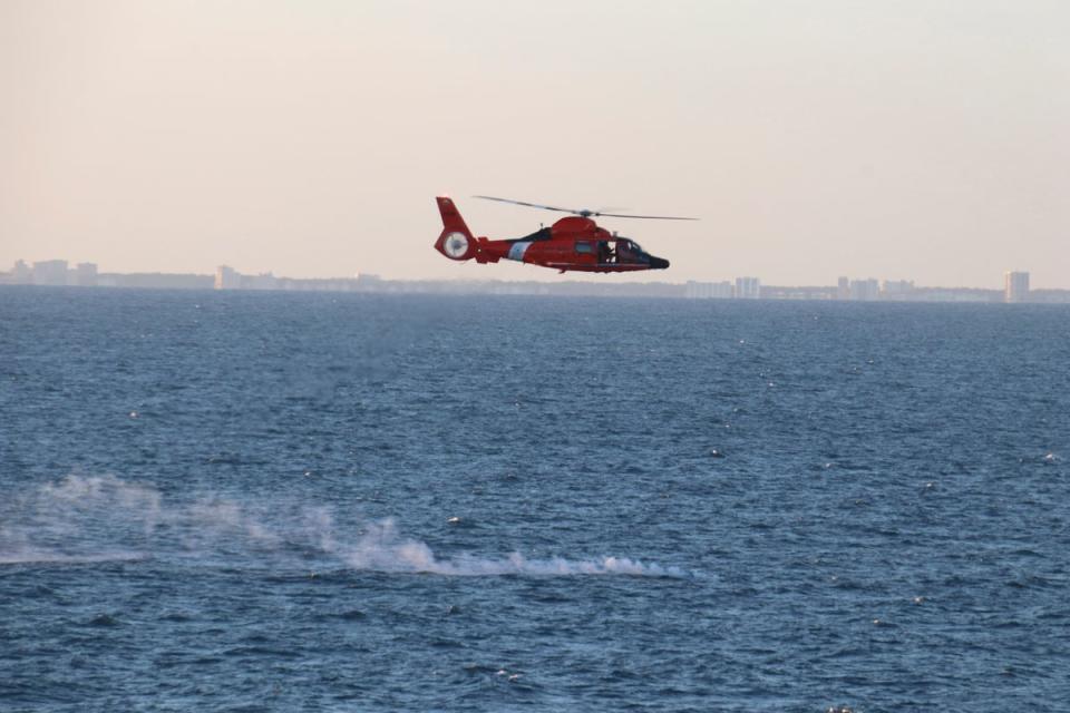 In this image provided by the US Navy, a US Coast Guard helicopter flies over a debris field during recovery efforts of a high-altitude surveillance balloon on 4 February (AP)