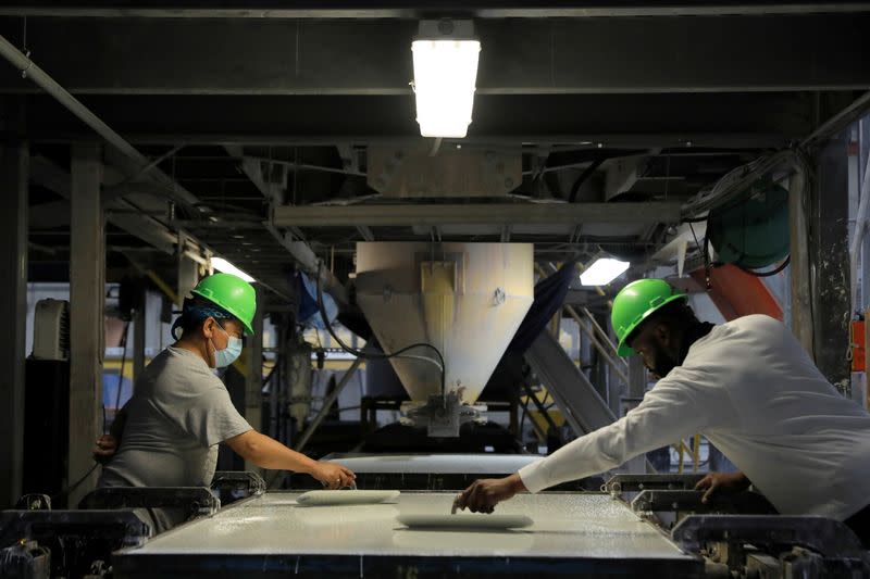 Workers trowel the poured mixture of a slab in the factory of IceStone, a manufacturer of recycled glass countertops and surfaces, in New York City