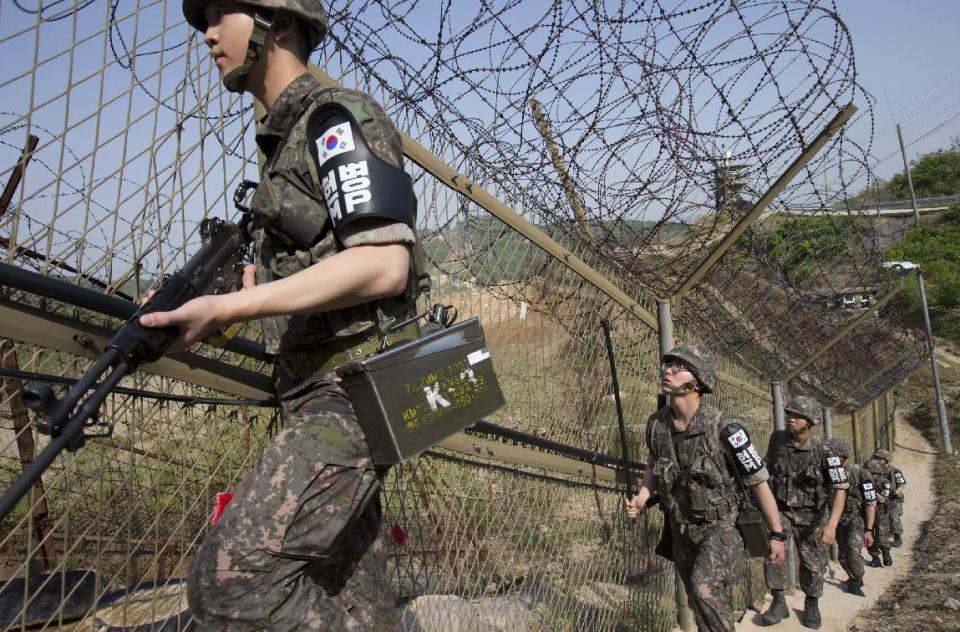 South Korean army soldiers patrol along the barbed-wire fence at the demilitarized zone (DMZ) in Cheorwon, South Korea, Tuesday, May 13, 2014. North Korea warned Tuesday that a South Korean official would pay a high price for saying the North "must disappear soon" in an escalation of rhetoric between the rivals. (AP Photo/Yonhap, Lim Byung-shik) KOREA OUT