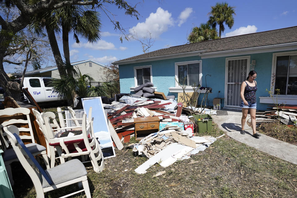 Christina Barrett walks among the water damaged furniture outside her home Tuesday, Oct. 4, 2022, in North Port, Fla. Residents along Florida's west coast are continuing to clean up after Hurricane Ian made landfall last week. (AP Photo/Chris O'Meara)
