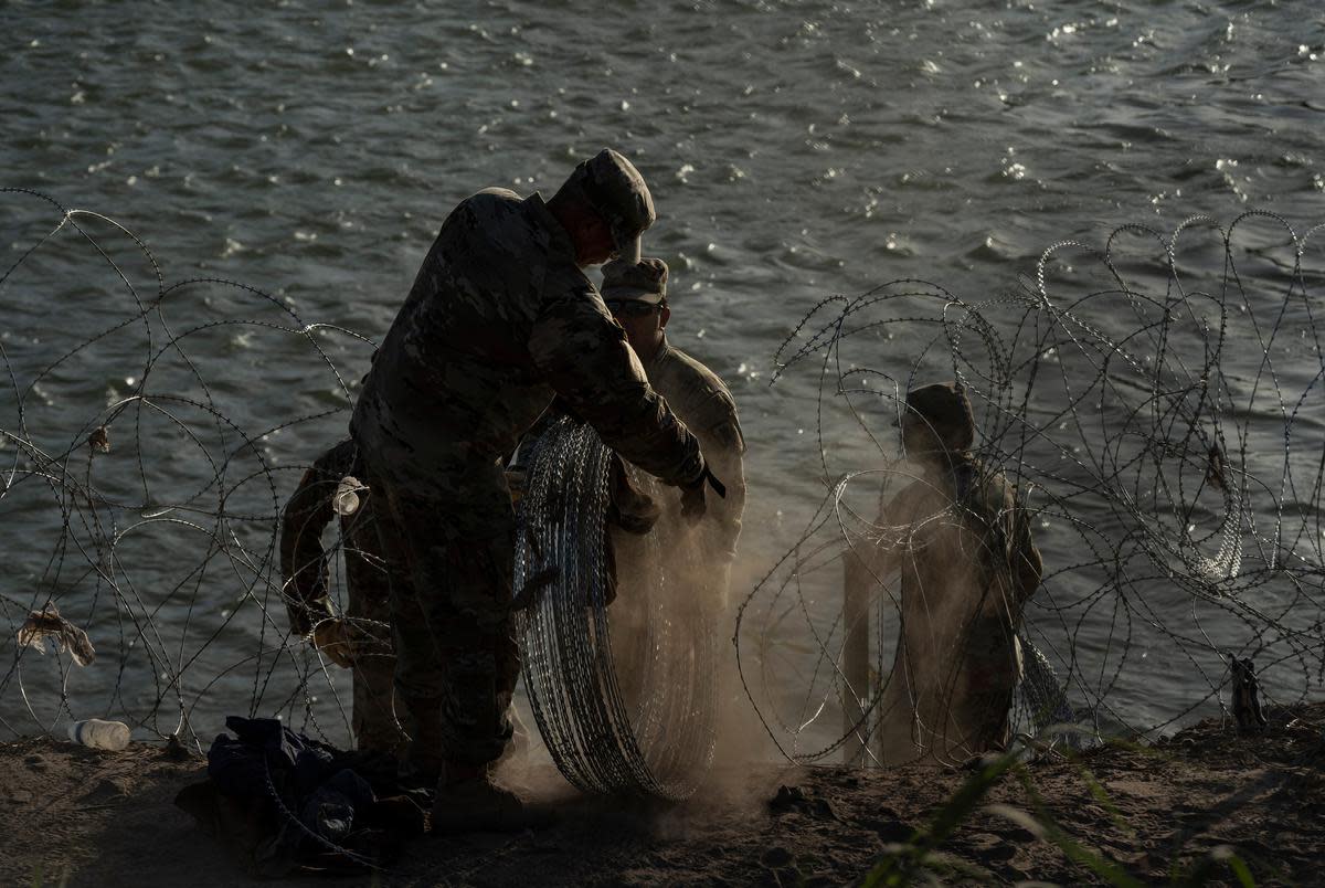 National Guard members install concertina wire along the river bank on private property owned by the Urbinas in Eagle Pass, Texas on July 28, 2023. 
Verónica G. Cárdenas for The Texas Tribune