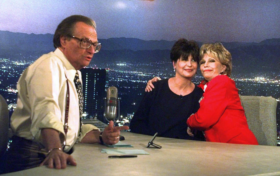 FILE - In this Dec. 12, 1997 file photo, Tina Sinatra, center, and Nancy Sinatra, right, daughters of the singer Frank Sinatra, joke around on CNN's Los Angeles set of "Larry King Live" as host Larry King makes preparations. King, who interviewed presidents, movie stars and ordinary Joes during a half-century in broadcasting, has died at age 87. Ora Media, the studio and network he co-founded, tweeted that King died Saturday, Jan. 23, 2021 morning at Cedars-Sinai Medical Center in Los Angeles. (AP Photo/Susan Sterner)