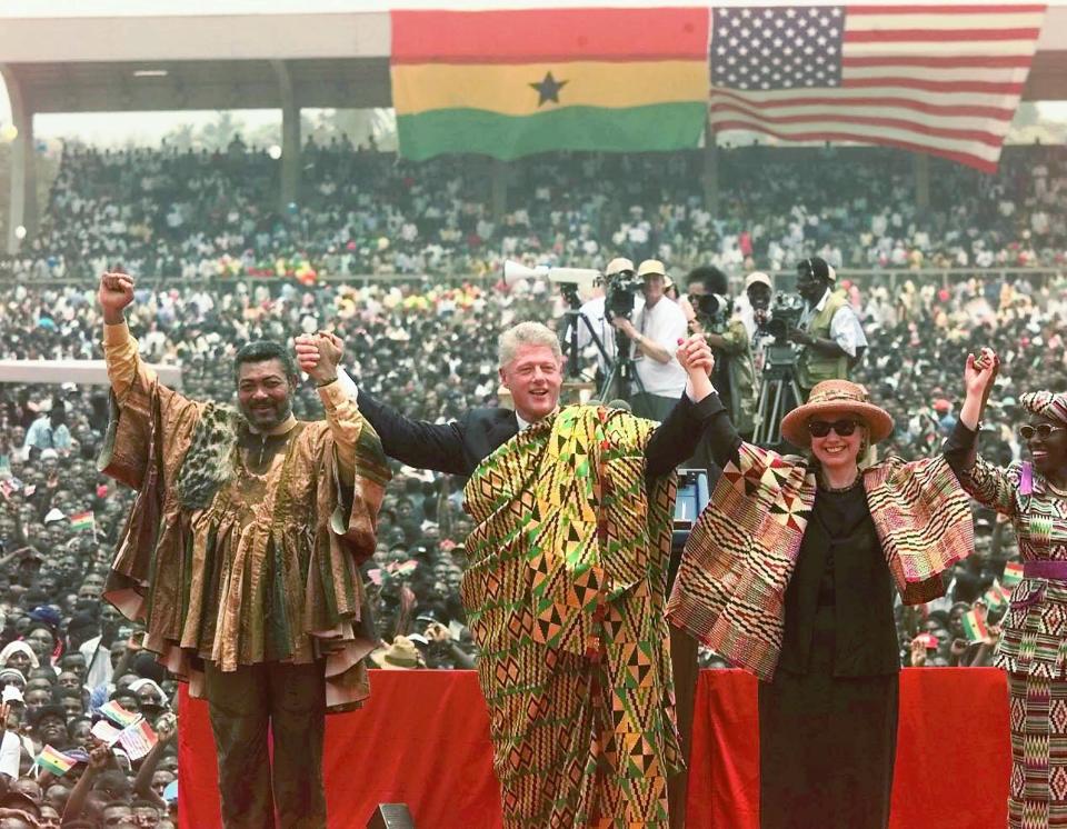 FILE - In this Monday, March 23, 1998 file photo, Ghana's President Jerry Rawlings, left, U.S. President Clinton, center, and U.S. First Lady Hillary Rodham Clinton, center-right, both wearing the Kente traditional Ghanaian dress, and Ghana's first lady Nana Rawlings, right, greet a crowd of over 200,000 people assembled in Independence Square in Accra, Ghana. Ghana's former president Jerry Rawlings, who staged two coups and later led the West African country's transition to a stable democracy, has died aged 73, according to the state's Radio Ghana and the president Thursday, Nov. 12, 2020. (AP Photo/Greg Gibson, File)