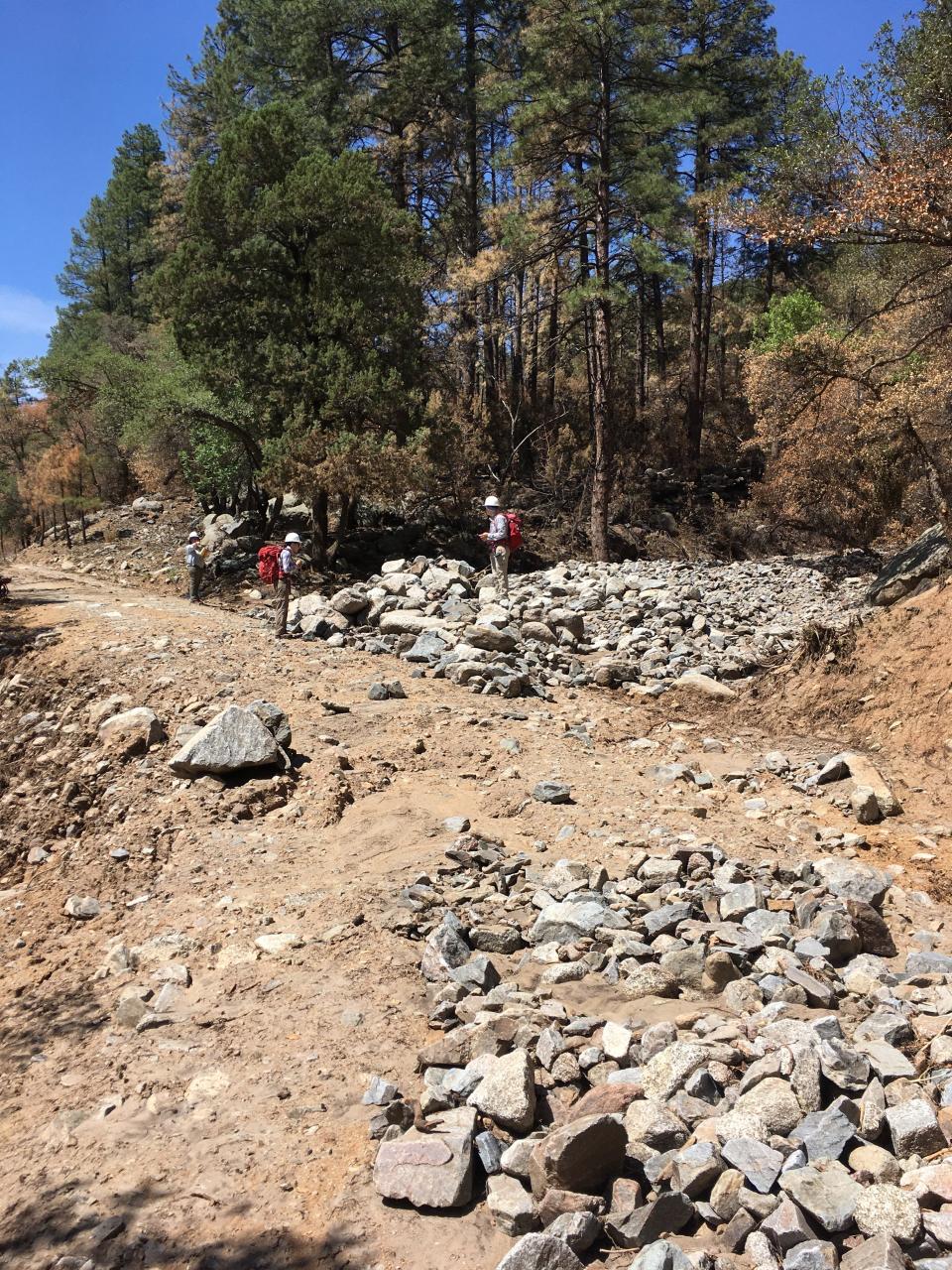 Ann Youberg, right, and University of Arizona graduate students Olivia Hoch, center, and Alexander Gorr examine a debris flow deposit in an area burned by the 2021 Telegraph Fire near Globe.