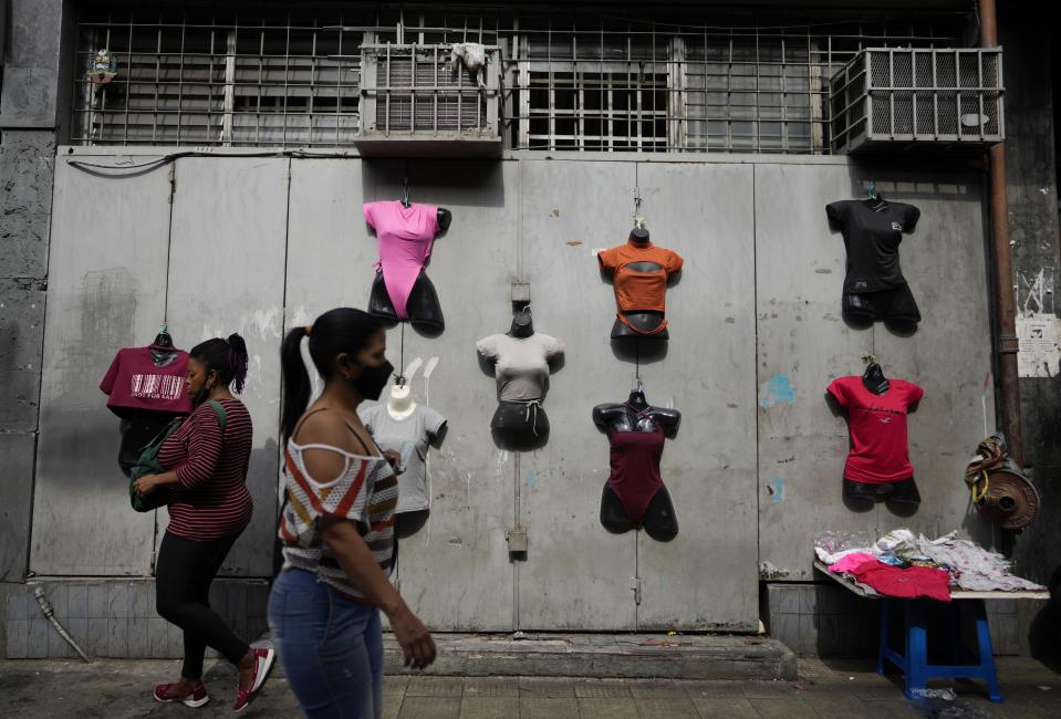 Residents walk past mannequins displaying women's clothes for sale in Caracas, Venezuela, Friday, Oct 1, 2021. A new currency with six fewer zeros debuts today in Venezuela, whose currency has been made nearly worthless by years of the world's worst inflation. The new currency tops out at 100 bolivars, a little less than $25 until inflation starts to eat away at that as well. (AP Photo/Ariana Cubillos)