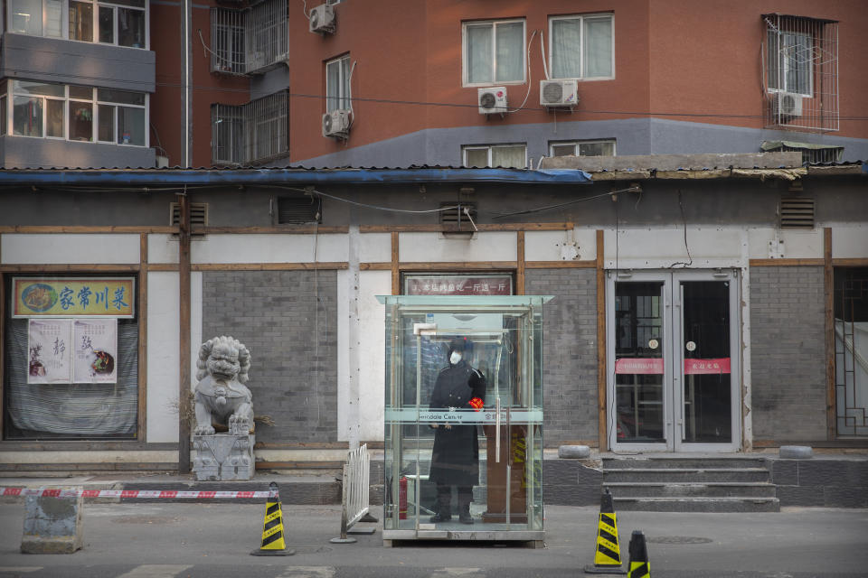 In this Monday, Jan. 27, 2020 photo, a security guard wearing a face mask stands in a glass cubicle on an empty street in Beijing. Fears of a virus outbreak have kept many indoors and at home in China's capital. Cultural landmarks such as the Great Wall and Forbidden City have closed their doors to visitors, nearly deserted shopping malls have reduced their operating hours, and restaurants that remain open draw just a handful of customers. (AP Photo/Mark Schiefelbein)