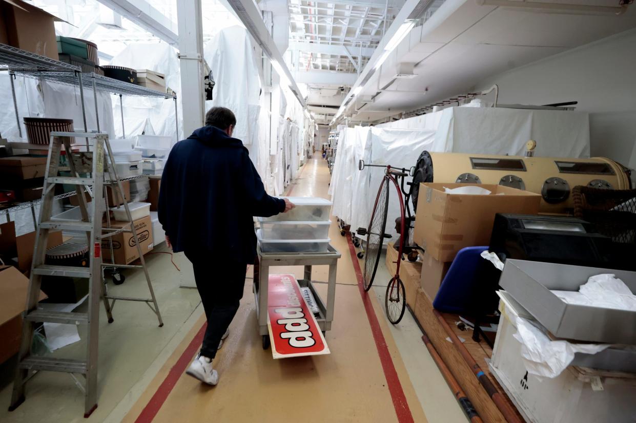 David Schneider, who has worked at the Detroit Historical Society’s Collections Resource Center in Detroit since 2002, pushes a cart as he passes by an old iron lung machine and a penny farthing bike while looking for Hudson’s items on Nov. 9, 2023. The items will be used for a "Hudsons for the Holidays" exhibition that the museum on Woodward Avenue in Detroit is getting ready to display later this month.