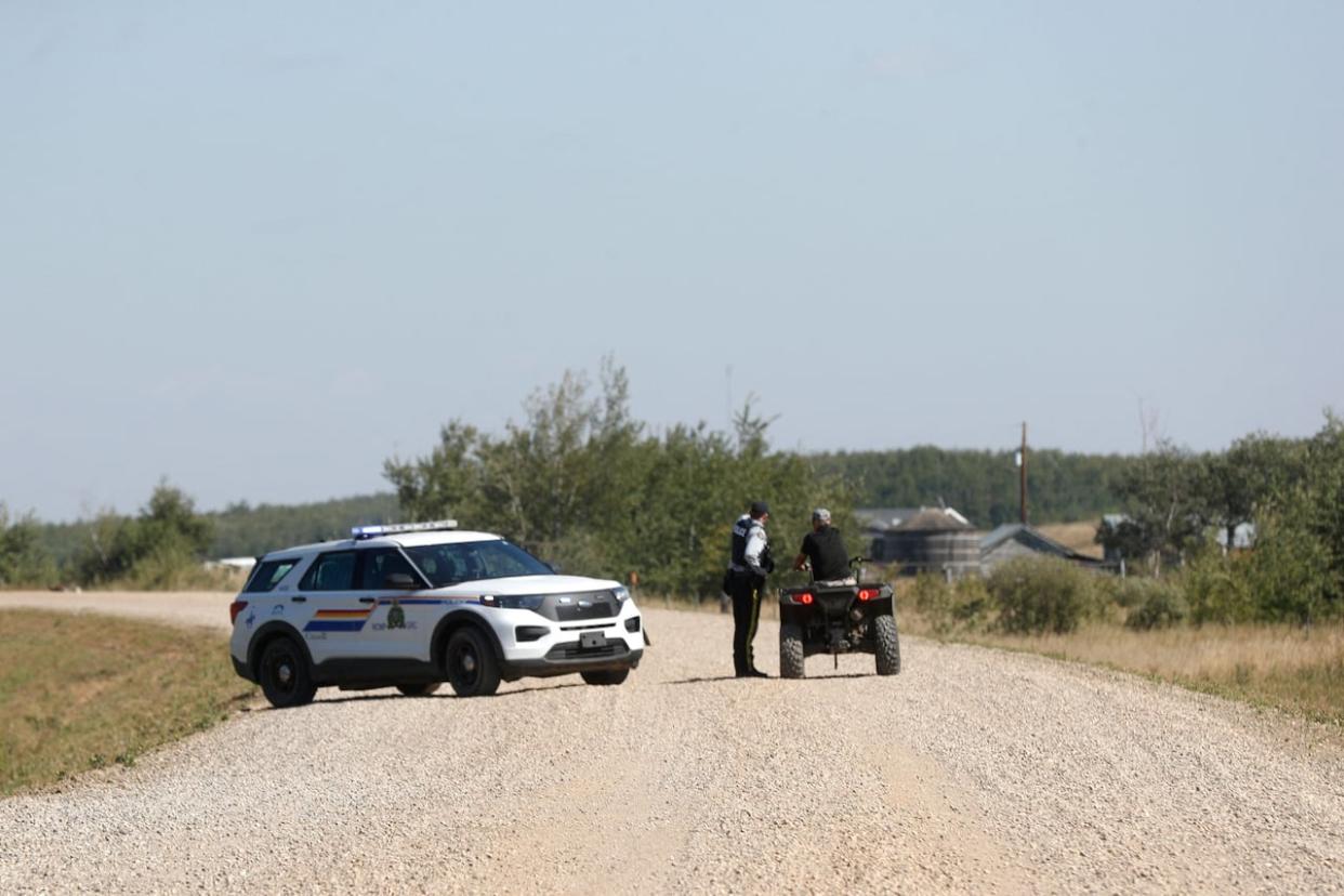 A police officer speaks with someone outside the James Smith Cree Nation in 2022.  (Lars Hagberg/AFP via Getty Images - image credit)