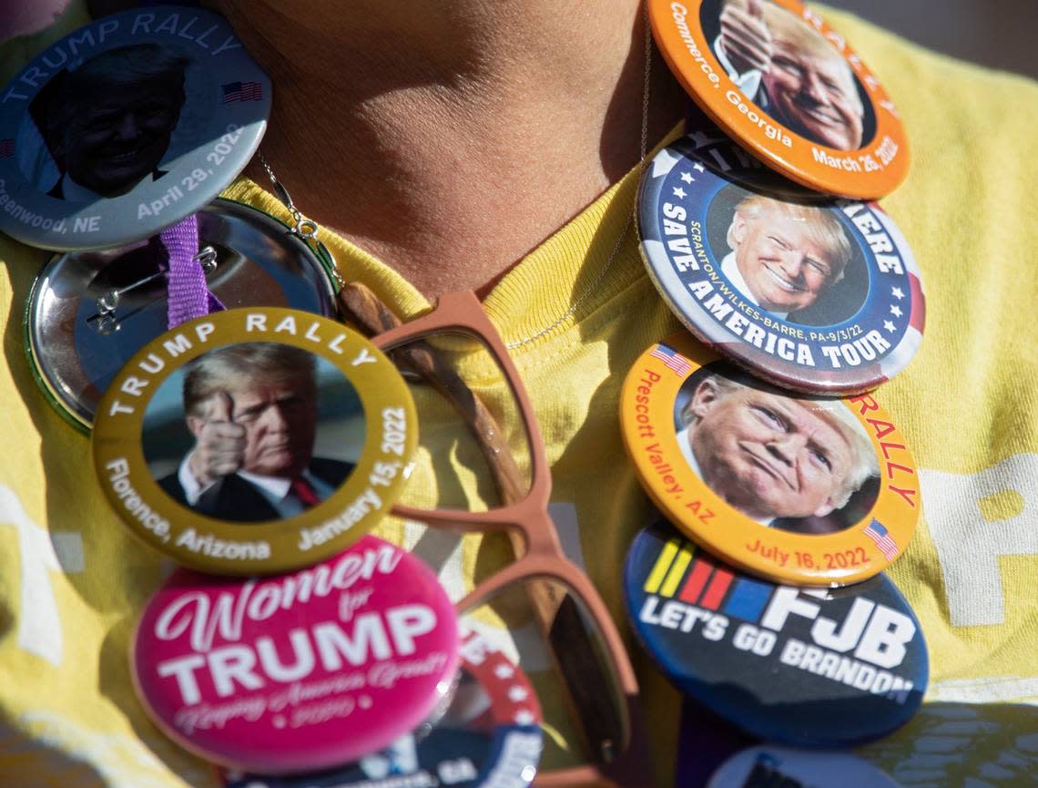 A person wears a necklace of buttons supporting former president Donald Trump prior to the start of a rally at Wilmington International Airport on Friday, Sept. 23, 2022.