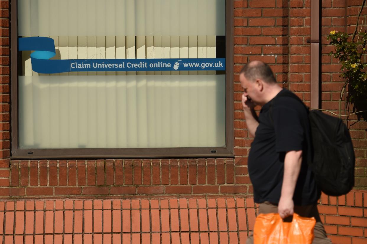 A man walks past a sign with the email address of 'universal credit' outside the offices of 'jobcentreplus' in Oldham, Lancashire on March 26, 2020, during a country-wide lockdown to slow the spread of the novel coronavirus COVID-19. (Photo by Oli SCARFF / AFP) (Photo by OLI SCARFF/AFP via Getty Images)