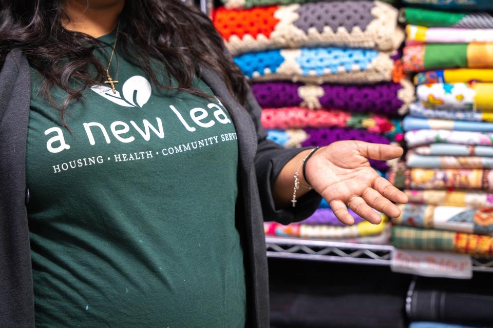 A New Leaf volunteer program supervisor Raven Jordan Yosick stands beside shelves of handmade quilt donations at La Mesita Family Homeless Shelter on Dec. 28, 2022, in Mesa.