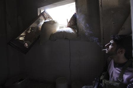 A Free Syrian Army fighter smokes while monitoring an area through a mirror inside a room in Deir al-Zor September 28, 2013. REUTERS/Khalil Ashawi
