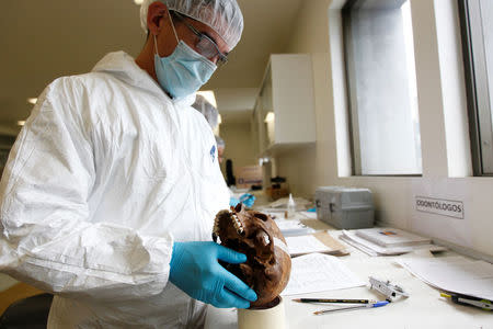 A forensic doctor examines the bones of an unidentified victim which is analyzed in the lab of the Attorney-General's office in Bogota, Colombia, May 5, 2017. REUTERS/Inaldo Perez