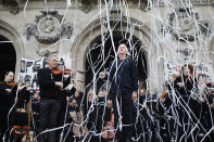 Michel Dietlin, center, stands with musicians of the orchestra outside the Palais Garnier opera house after performing Saturday, Jan. 18, 2020 in Paris. As some strikers return to work, with notable improvements for train services that have been severely disrupted for weeks, more radical protesters are trying to keep the movement going. (AP Photo/Kamil Zihnioglu)