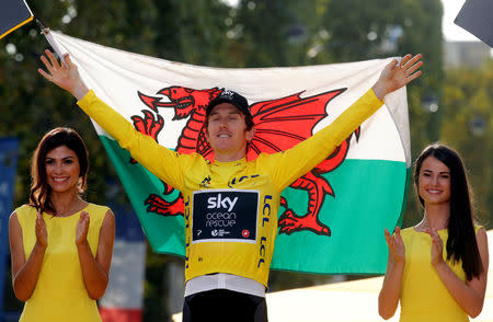 FILE PHOTO: Cycling - Tour de France - The 116-km Stage 21 from Houilles to Paris Champs-Elysees - July 29, 2018 - Team Sky rider Geraint Thomas of Britain celebrates his overall victory on the podium with a Welsh flag. REUTERS/Philippe Wojazer/File Photo