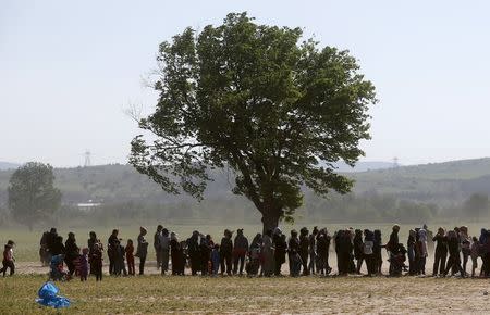 People line up for food during heavy winds at a makeshift camp for migrants and refugees at the Greek-Macedonian border near the village of Idomeni, Greece, April 20, 2016. REUTERS/Stoyan Nenov