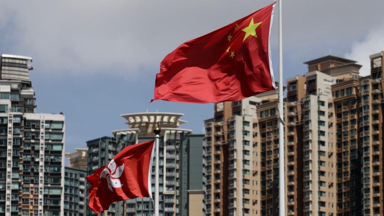 Die Flagge der Sonderverwaltungszone Hongkong (l) und die Flagge der Volksrepublik China wehen vor Wolkenkratzern.(Symbolbild)