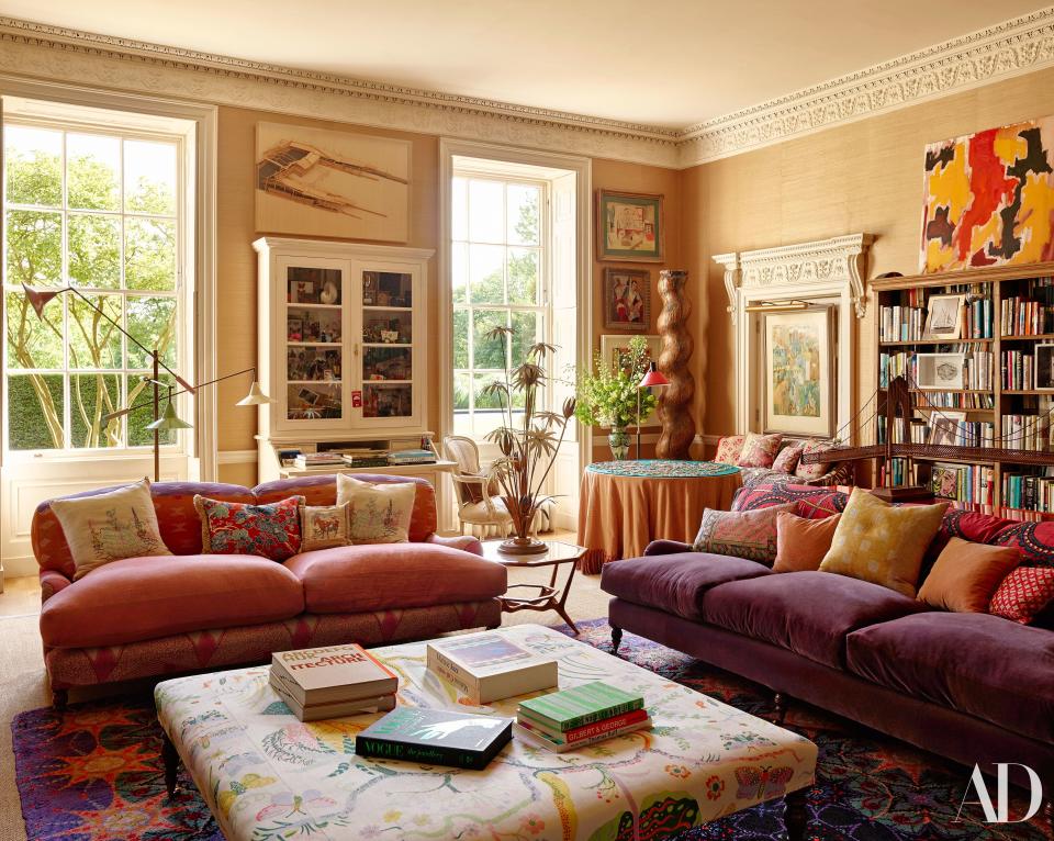 In the sitting room, George Smith sofas, one upholstered with Pakistani marriage quilts (left) and the other a Brunschwig & Fils velvet, face an ottoman clad in a Josef Frank fabric. The tri-arm floor lamp and flower lamp are London antiques-market finds; PAR puzzle on back table; paintings by Tadashi Kawamata, Axel Kulle, and Billy Metcalfe.