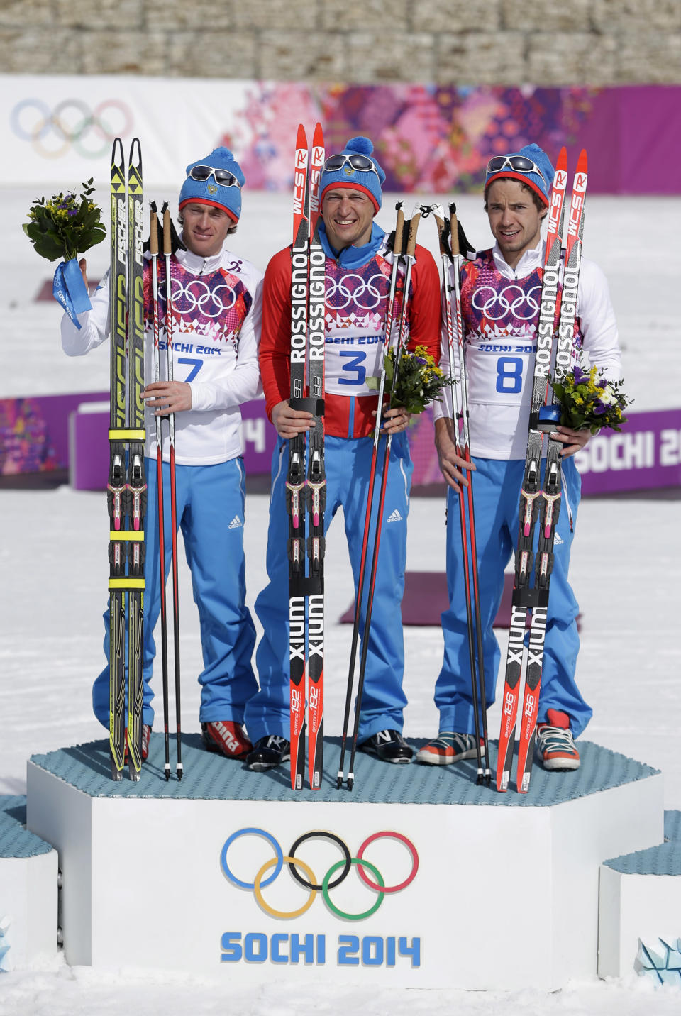 Russia's gold medal winner Alexander Legkov is flanked by Russia's silver medal winner Maxim Vylegzhanin, left and Russia's bronze medal winner Ilia Chernousov during the flower ceremony of the men's 50K cross-country race at the 2014 Winter Olympics, Sunday, Feb. 23, 2014, in Krasnaya Polyana, Russia. (AP Photo/Matthias Schrader)