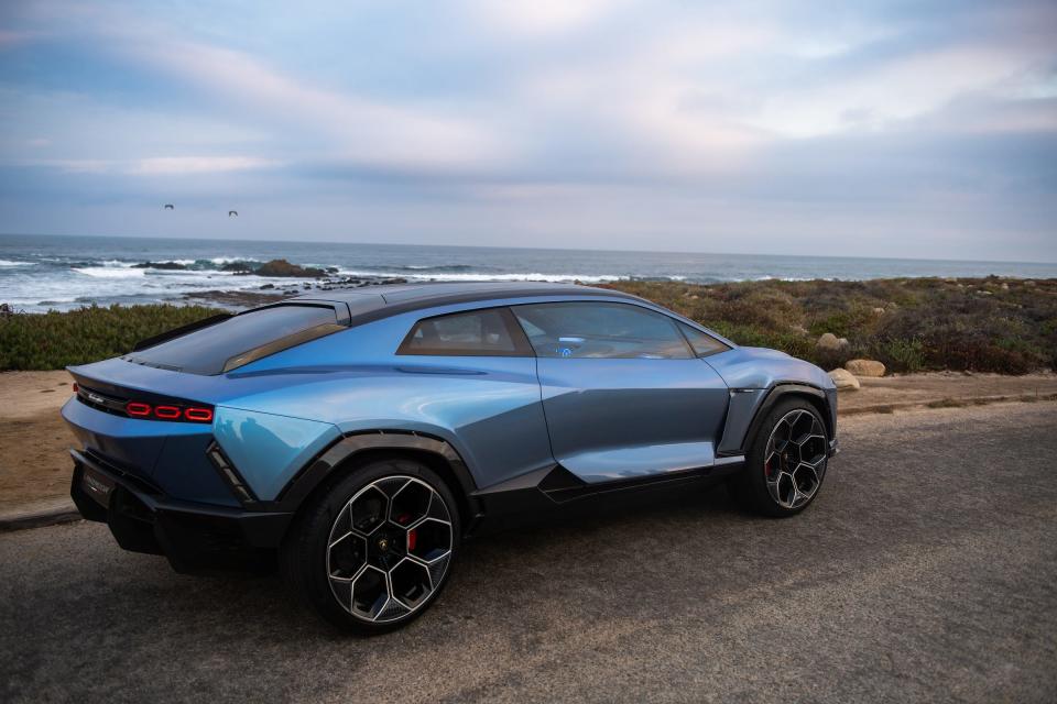 The Lamborghini Lanzador concept car against a rocky beach and blue cloudy sky.