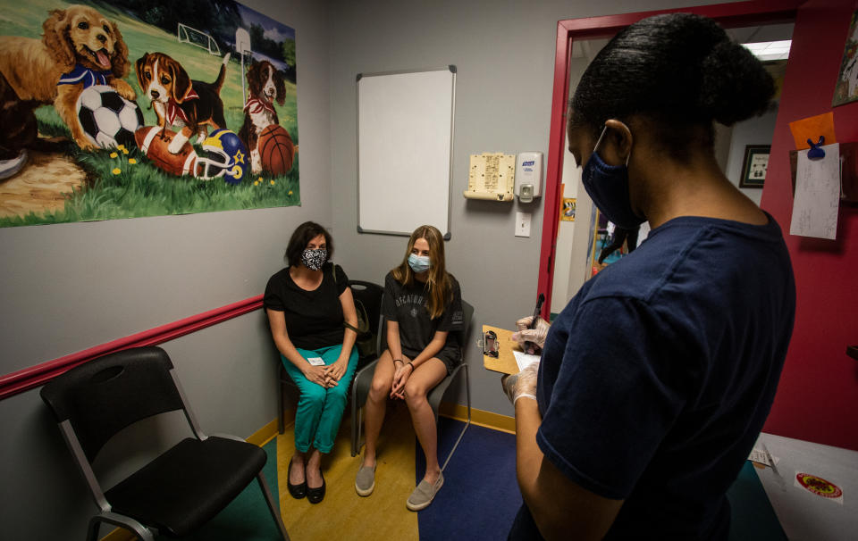 Middle school student Meredith Rogers, center, waits to receive her first coronavirus vaccination on Wednesday, May 12, 2021, in Decatur, Ga. Hundreds of children, ages 12 to 15, received the Pfizer vaccine at the DeKalb Pediatric Center, just days after it was approved for use within their age group. (AP Photo/Ron Harris)