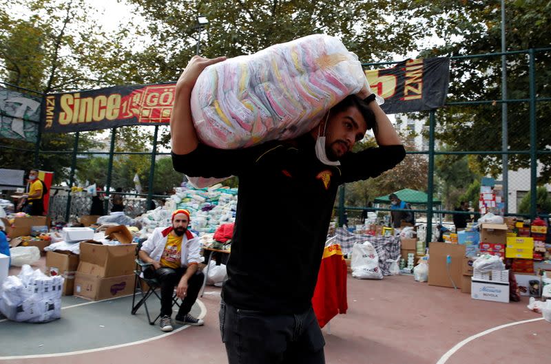A man carries a bag of clothing aid for survivors as it is collected at a basketball court after an earthquake struck the Aegean Sea, in the coastal province of Izmir
