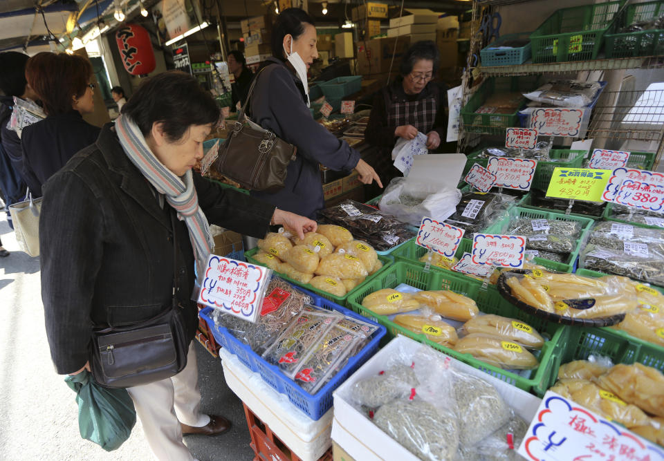 Shoppers buy dry seafood at Tsukiji fish market in Tokyo, Friday, March 28, 2014. Japanese household spending fell 1.5 percent in February from a year earlier, suggesting consumers are tightening belts ahead of an April 1 hike in the country's sales tax. The government also reported Friday, March 28 that core consumer prices rose 1.3 percent in February, though a large share of the increase was due to rising energy costs. (AP Photo/Eugene Hoshiko)