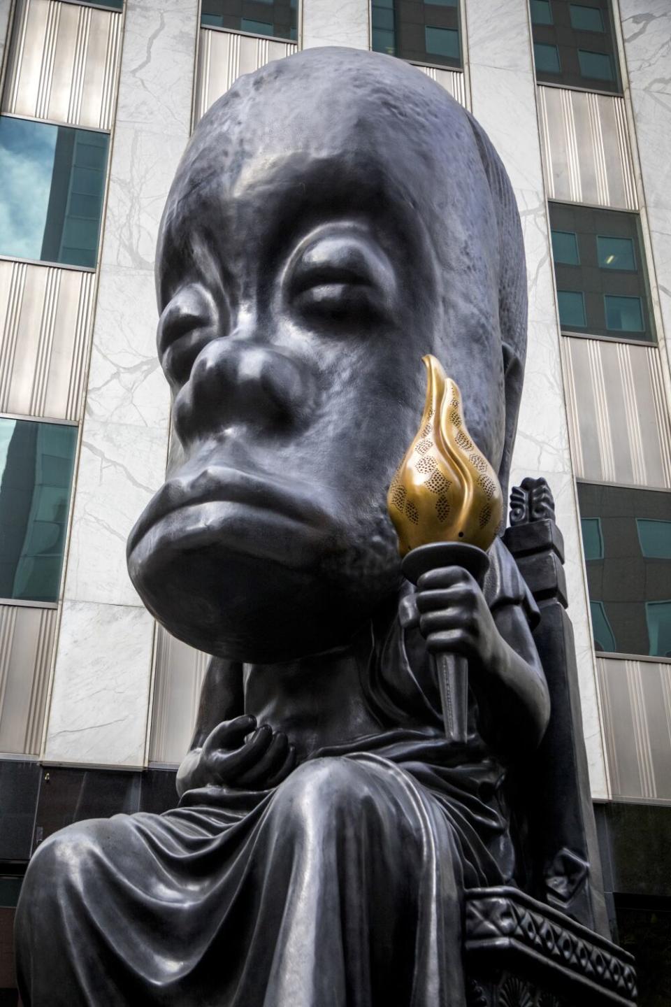 A large sculpture of figure holding a golden flame.