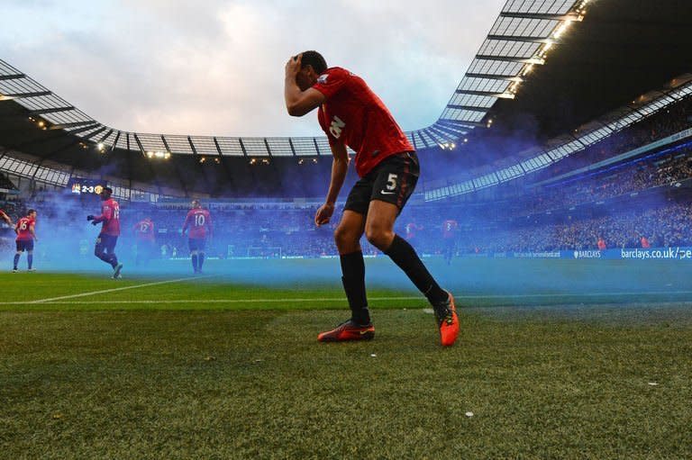 Manchester United defender Rio Ferdinand reacts after being struck by an object thrown from the crowd during the English Premier League match between Manchester City and Manchester United at the Etihad stadium in Manchester. Ferdinand laughed off the incident that saw him struck in the face by a coin as he celebrated Manchester United's winning goal in their 3-2 success