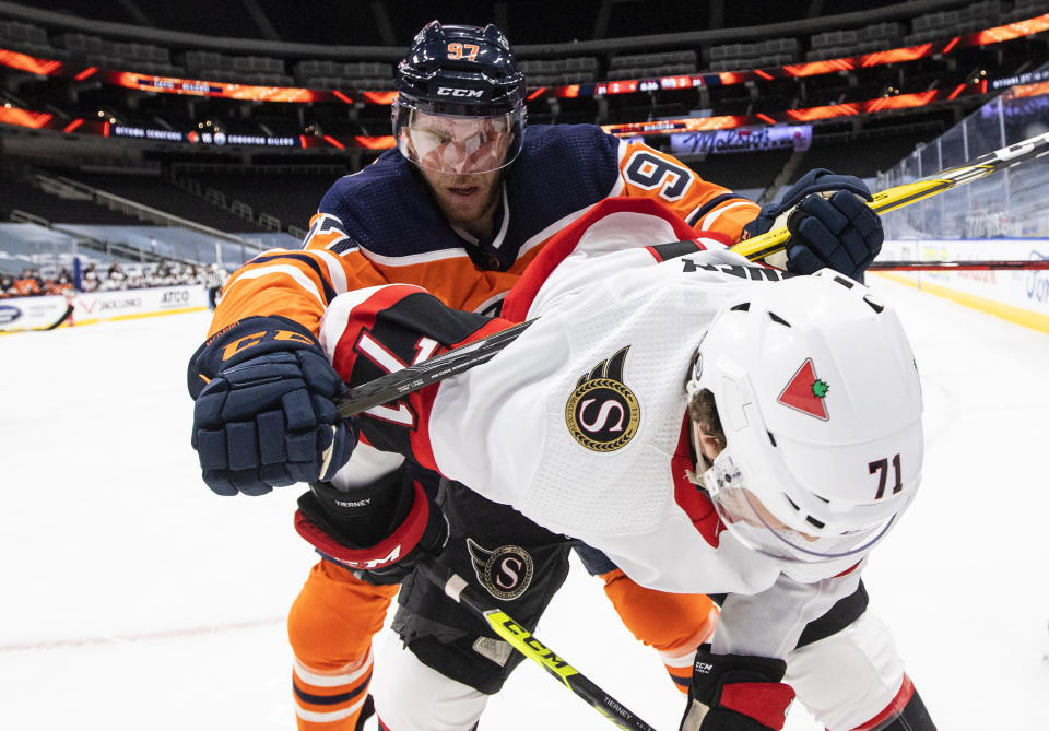 Edmonton Oilers' Connor McDavid (97) checks Ottawa Senators' Chris Tierney (71) during third-period NHL hockey game action in Edmonton, Alberta, Monday, March 8, 2021. (Jason Franson/The Canadian Press via AP)