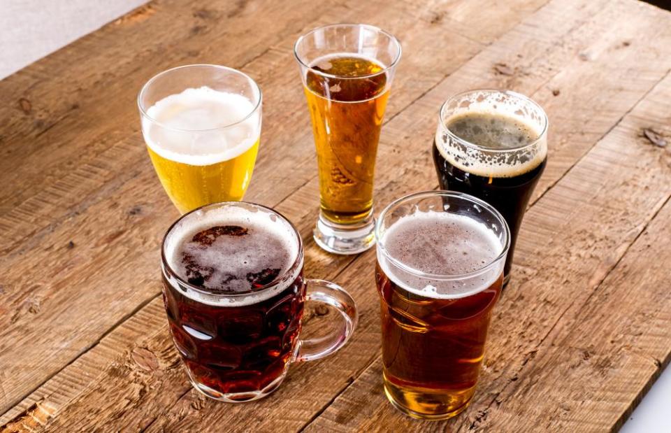 A selection of beers in different glasses, arranged in a circle on a wooden table