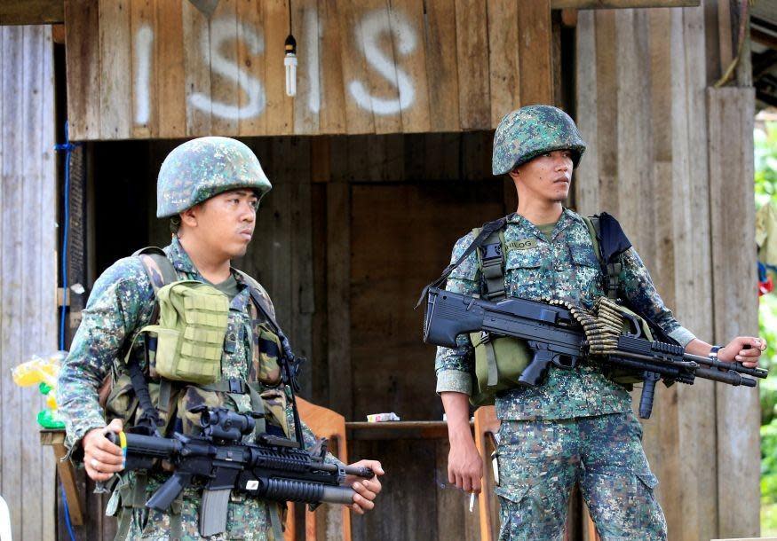 Soldiers stand guard along the main street of Mapandi village (REUTERS)