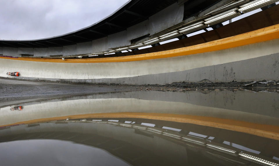 Latvia's Tomass Dukurs is seen on the track reflected in a puddle during the men's skeleton test event at the "Sanki" siding center in Rosa Khutor, a venue for the Sochi 2014 Winter Olympics near Sochi February 15, 2013. Although many complexes and venues in the Black Sea resort of Sochi mostly resemble building sites that are still under construction, there is nothing to suggest any concern over readiness. Construction will be completed by August 2013 according to organizers. The Sochi 2014 Winter Olympics opens on February 7, 2014. REUTERS/Kai Pfaffenbach (RUSSIA - Tags: BUSINESS CONSTRUCTION CITYSCAPE ENVIRONMENT SPORT OLYMPICS SKELETON TPX IMAGES OF THE DAY) - RTR3DTZK