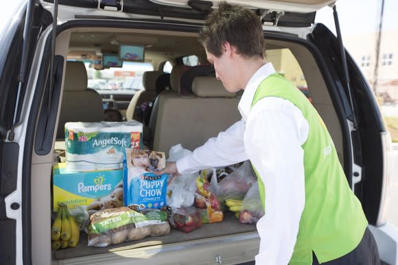 A Walmart associate loading a car full of groceries.