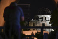 A visitor prays in front of the Atomic Bomb Dome in Hiroshima, western Japan early Friday, Aug. 6, 2021. Hiroshima on Friday marked the 76th anniversary of the world's first atomic bombing of the city. (Kyodo News via AP)